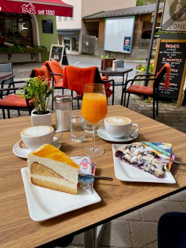 Tisch mit Kaffee, Saft, Kuchen und frischer Minze in einem Café.