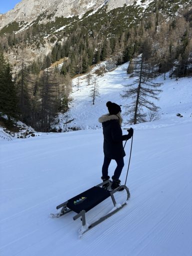 Eine Person beim Rodeln am Jenner in einer verschneiten Landschaft in den Bergen in Berchtesgaden. 