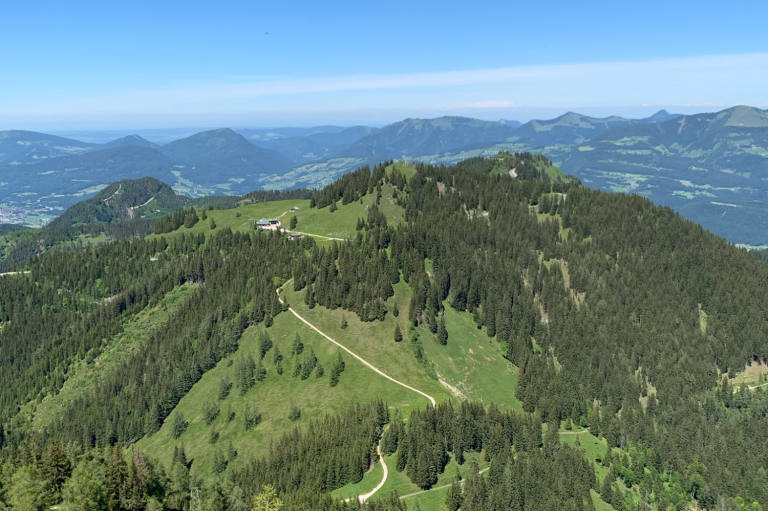 Berglandschaft des Rossfelds mit grünen Hügeln und einem blauen Himmel im Hintergrund.