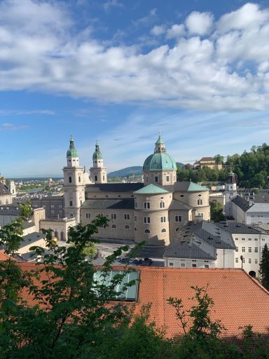 Blick auf die Stadt Salzburg mit historischen Gebäuden und grünen Hügeln im Hintergrund.