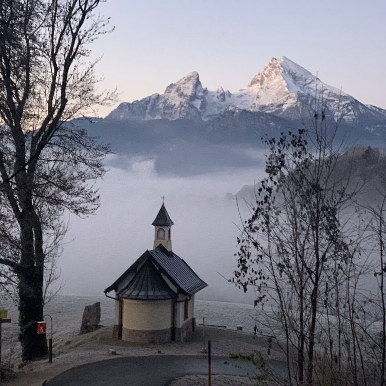 Kirchleitnkapelle im Vordergrund, im Hintergrund schneebedeckter Watzmann und Nebel im Tal.
